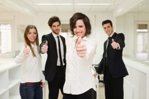 Portrait of cheerful businessteam giving thumbs up with a young woman as leader